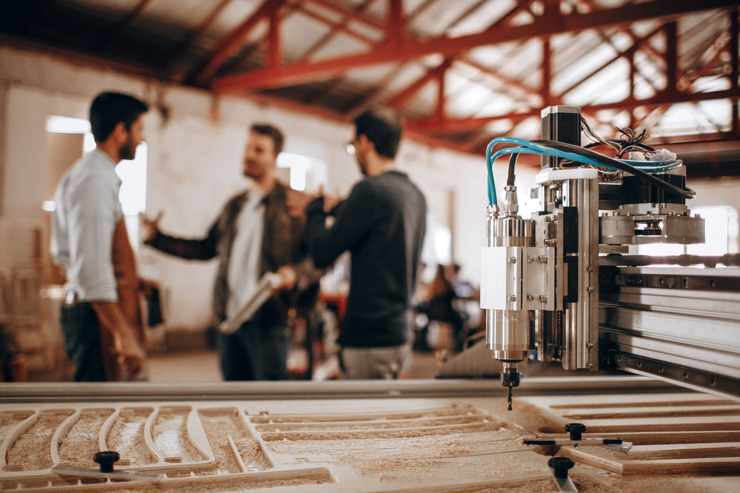 Collega's overleggen in een werkplaats naast een CNC-machine